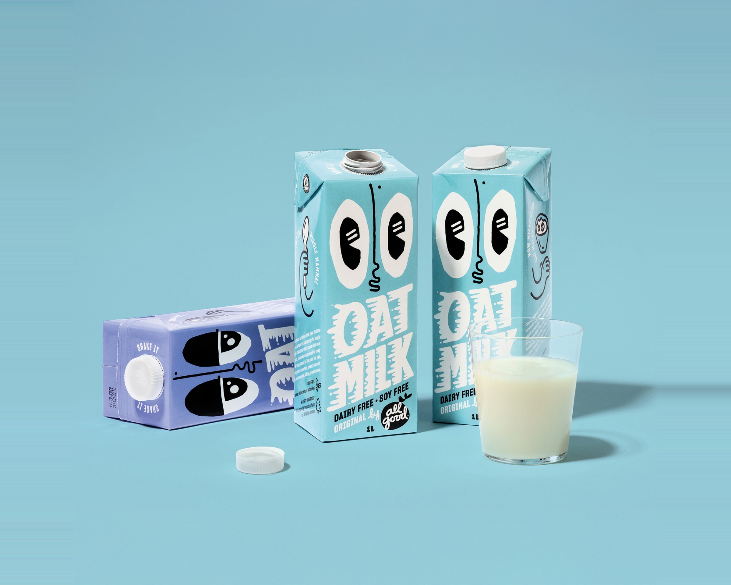 All Good Oat Milk — three cyan cartons, one open with cap beside it, and a glass of oat milk on a blue ground