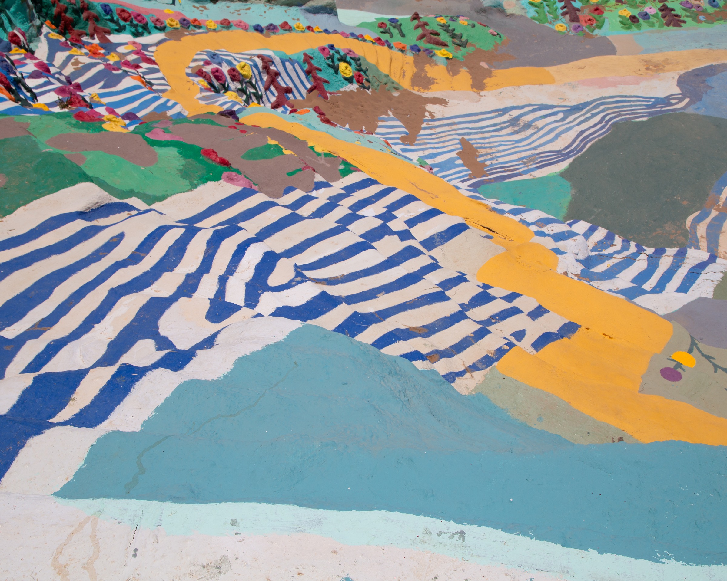 Close-up of the painted slopes — yellow rivers running through blue-and-white striped fields and beds of flowers